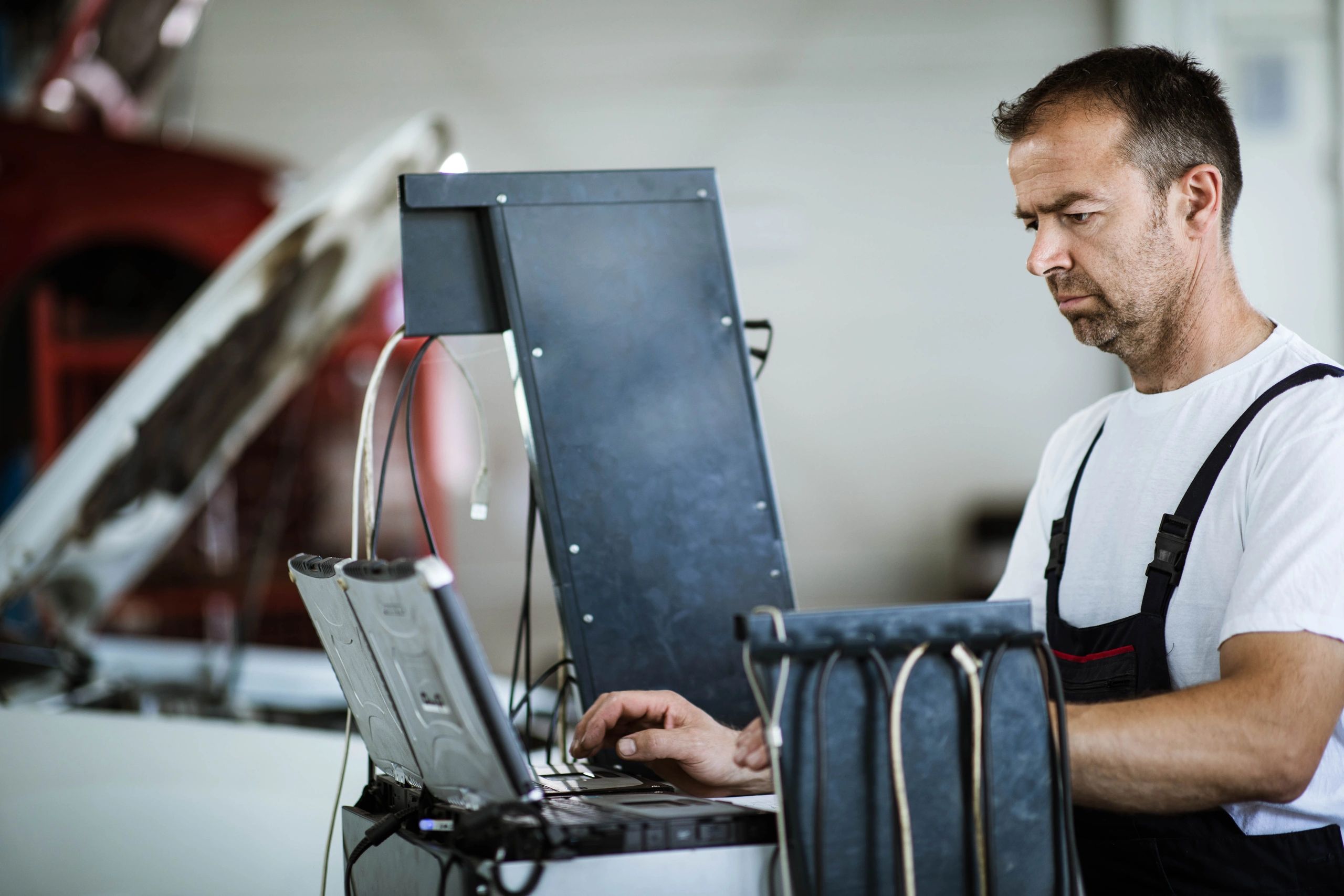 Technician using a laptop for vehicle diagnostics in a workshop
