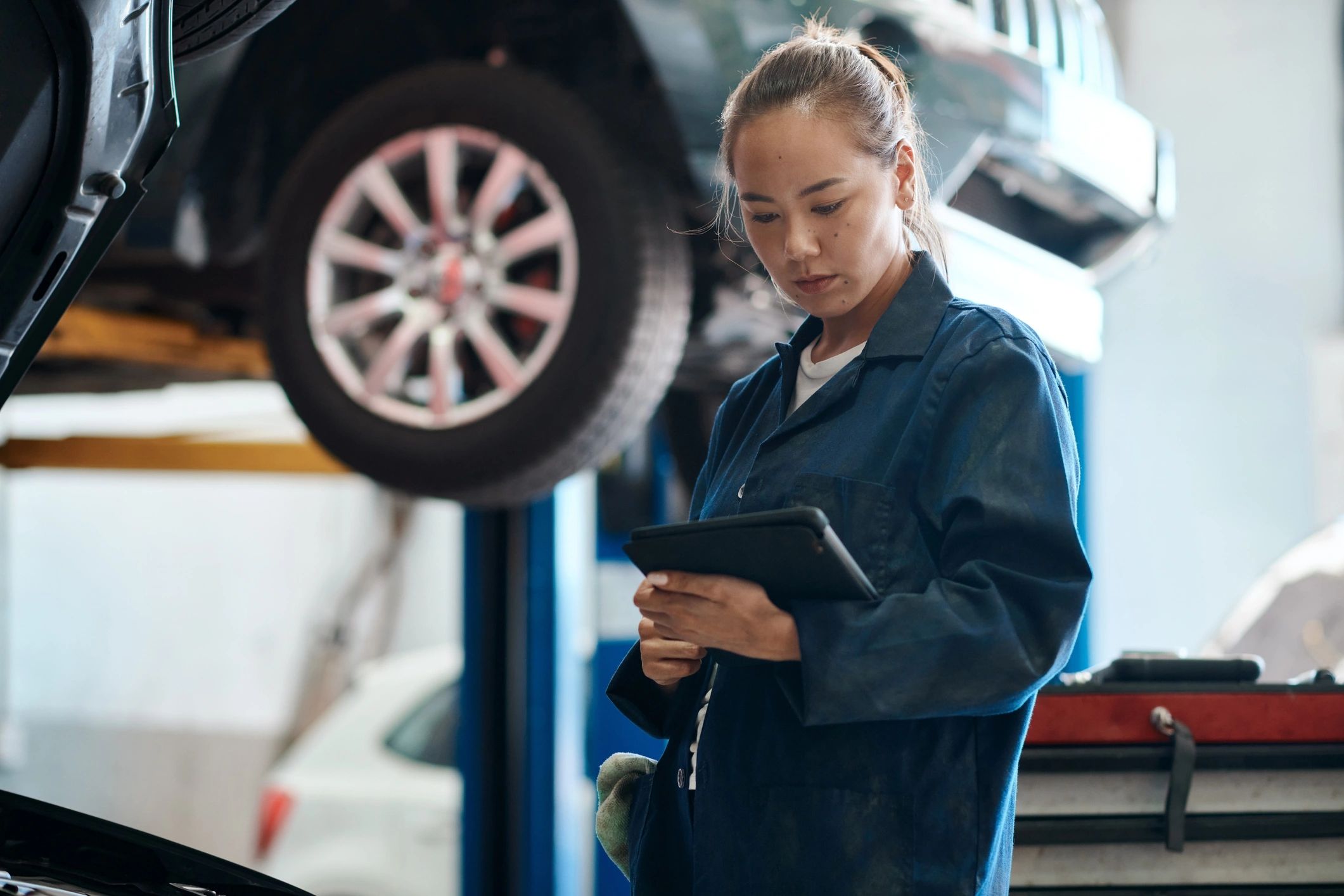 Technician using a tablet for vehicle diagnostics in a repair shop