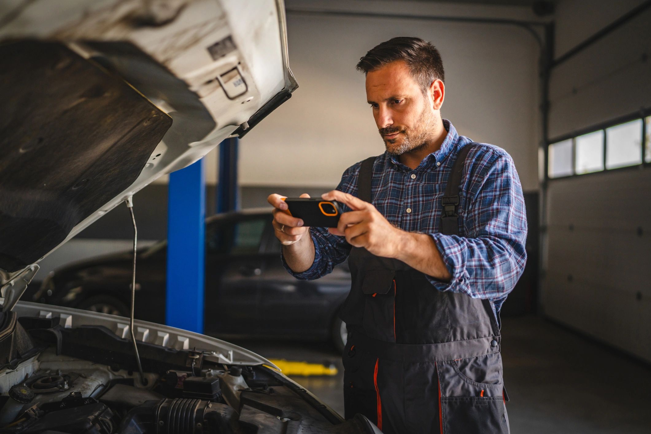 Mechanic photographing an engine bay as part of a diagnostic inspection